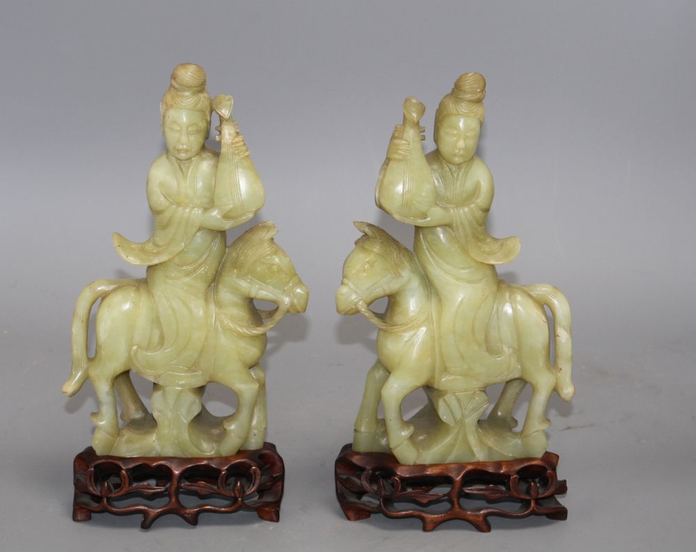 A pair of Chinese bowenite jade groups of a lady riding a horse, wood stands total height 26.5 and 27cm